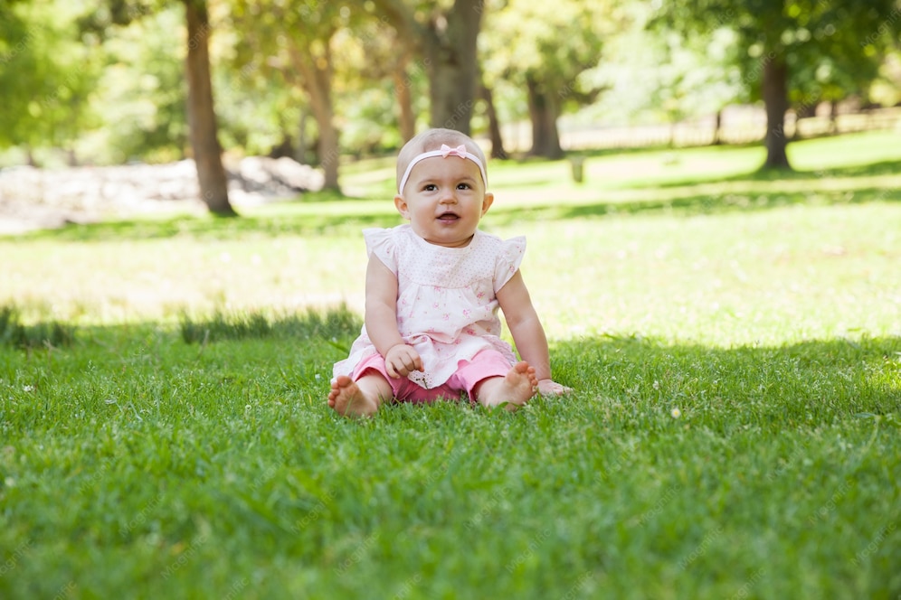  Happy cute baby sitting on grass at park 
